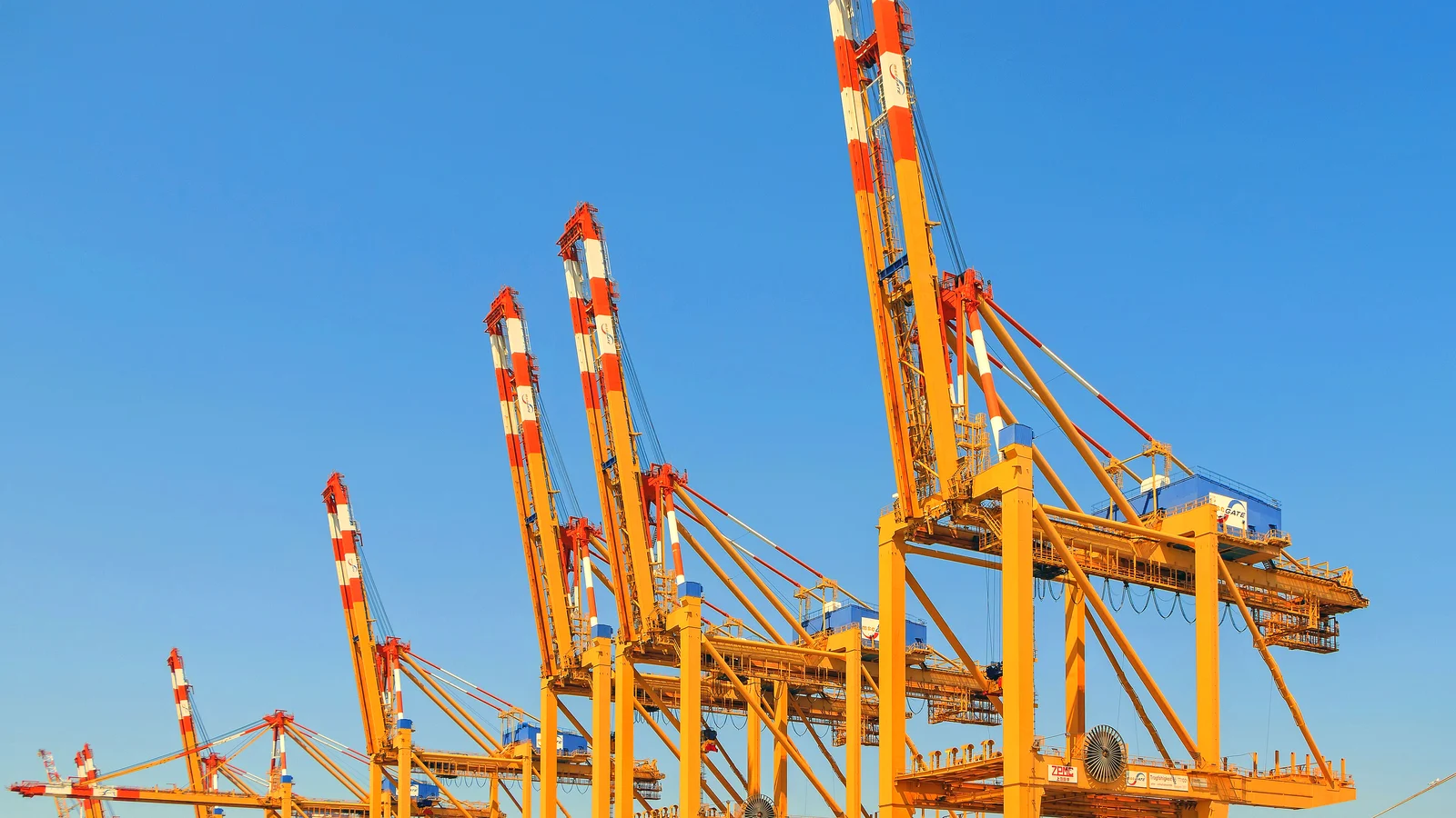 Orange and white container gantry cranes against a clear blue sky at Bremerhaven