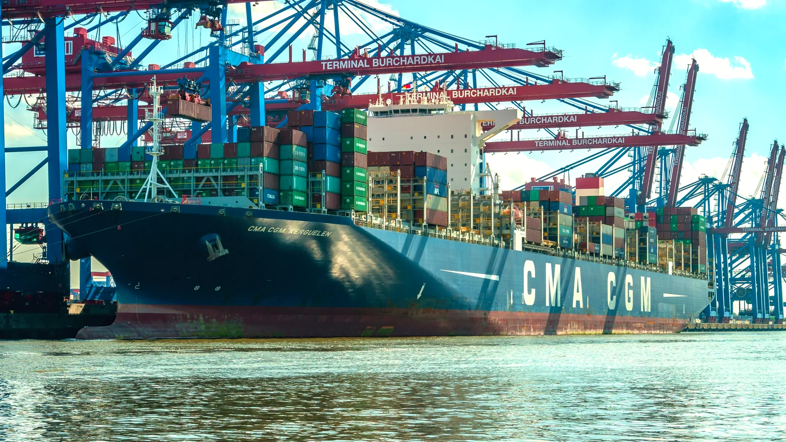 CMA CGM container ship loaded with colourful boxes under gantry cranes in Hamburg
