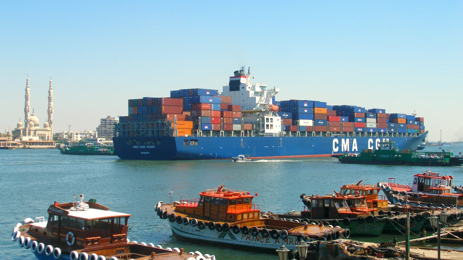 Container ship CMA CGM Puget transiting the Suez Canal past the town waterfront