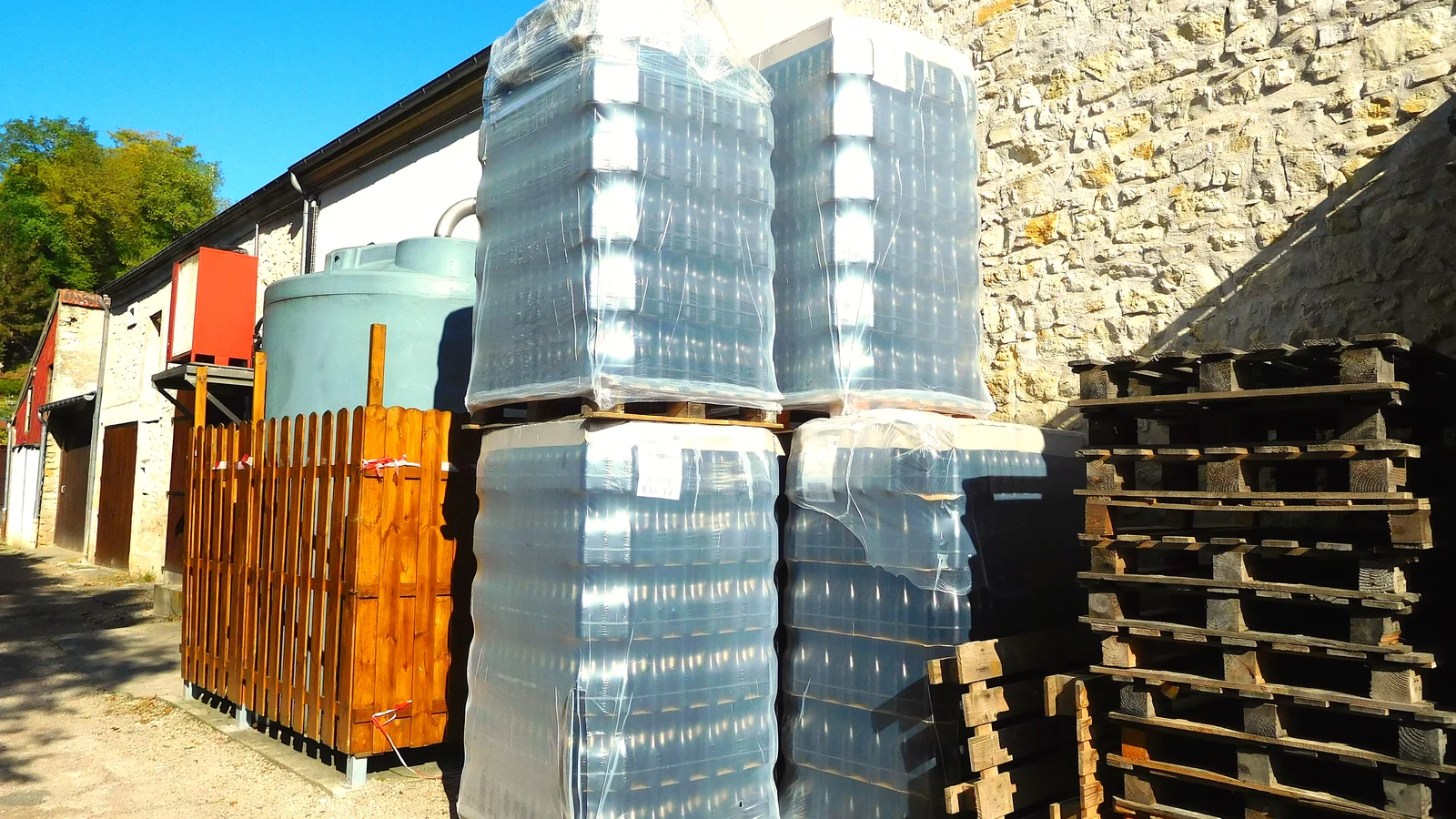 Wine bottle pallets wrapped in stretch film next to stacked wooden pallets